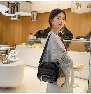 Détail du sac bandoulière en toile noire avec oreilles de chat et porte-clé ours