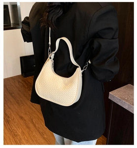 Detailed view of beige woven crescent bag with smooth shoulder strap and silver hardware