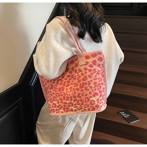 Detailed view of pink leopard print canvas tote bag with reinforced handles on a model