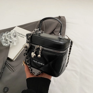 Detail of black quilted leather box bag featuring silver zippers and a heart pendant