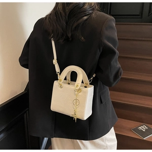 Detail of white embossed leather handbag with cartoon bear and star charm on stairs