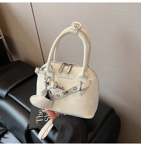 Détail d'un sac bandoulière blanc en cuir verni brillant avec pendentif en cœur