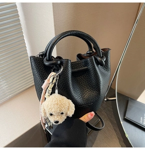 Close-up of black pebble grain leather bucket bag with teddy dog charm and drawstring