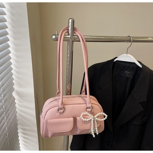 Close-up of pink Boston bag with textured leather, front pockets and pearl bow charm