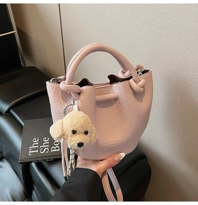 Détail du sac seau rose en cuir grainé avec cordon et breloque en peluche pour chien