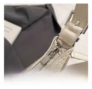 Detail of silver hardware and crocodile embossed texture on a cream crescent bag