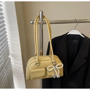 Detail of ginger bowling bag with pearl bow, heart charm and dual front pockets