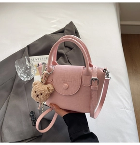 Detailed shot of pink litchi grain handbag with cute bear charm and adjustable strap