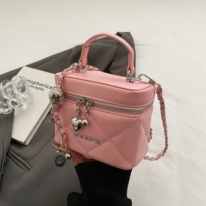 Detail view of pink quilted box bag with silver heart charm and chain strap