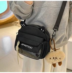 Détail du sac bandoulière noir avec oreilles de chat, fenêtre et pendentif ours