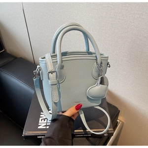 Detail of light blue lychee pattern bucket bag with silver heart charm and leather straps
