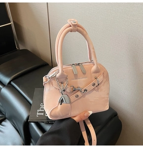 Détail du sac coquille en cuir verni rose avec zips argentés et breloque en cœur
