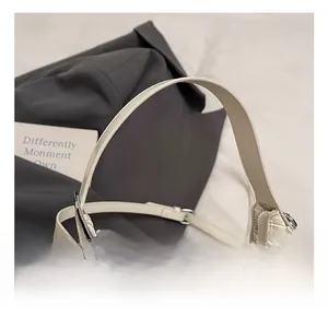 Detail of white hobo bag showing woven texture, adjustable strap and silver metal buckle