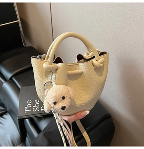 Détail du sac seau beige grainé avec cordon de serrage et pendentif caniche doux