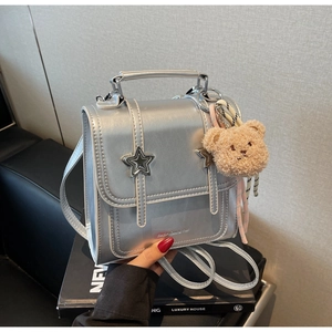 Silver metallic mini backpack detail featuring a star buckle and plush bear pendant