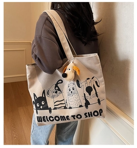 Detail of canvas tote bag with cartoon print and plush dog charm worn on shoulder