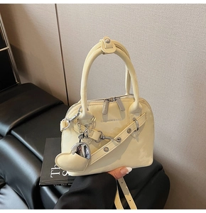 Détail du sac à main beige avec pendentif en forme de cœur et finitions en métal argenté