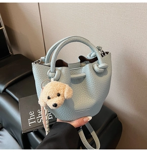 Détail du sac seau bleu clair à motif lychee avec pendentif en peluche chiot kaki