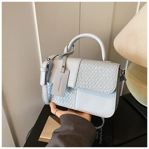 Détail du sac bandoulière bleu clair avec texture tissée et étiquette de mode