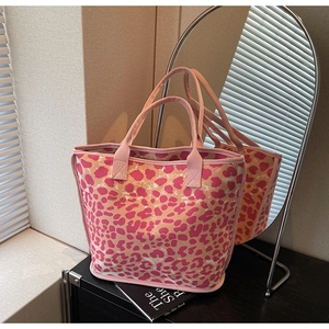 Detail of pink leopard print canvas tote bag reflected in a modern oval mirror