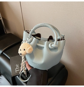 Close-up of light blue lychee pattern bucket bag with cute dog plush charm and drawstring