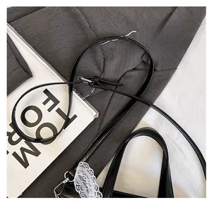Detail of black PU crossbody bag with adjustable strap and white lace decoration