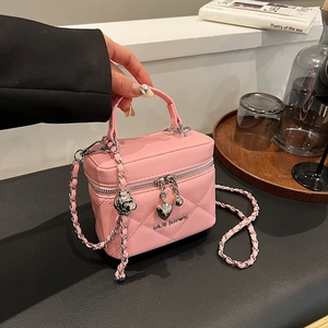 Detail view of pink quilted box bag with heart charm and gold metal logo lettering