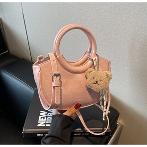 Pink crescent handbag with wrinkled patent leather finish and cute teddy bear charm