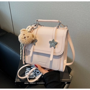 Detail view of pink glossy PU backpack featuring metallic star studs and a plush bear charm