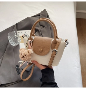 Detail of two-tone PU leather handbag with bear charm and adjustable shoulder strap