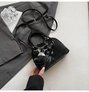 Détail du sac coquille noir brillant à motif marbré avec pendentif coeur et métal