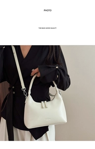 Close-up of a white minimalist half-moon bag with double zipper and detachable strap
