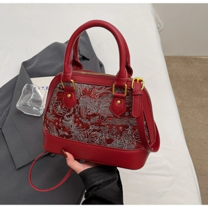 Detail of red shell bag with floral bird embroidery and golden metal hardware
