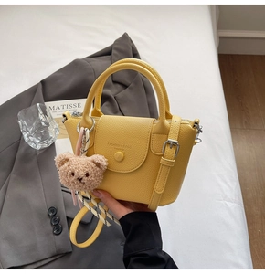 Detail of yellow lychee leather bucket bag with a cute brown bear charm accessory