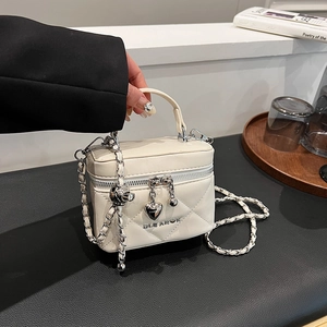 Detailed view of quilted white leather mini bag with silver heart charm and chain strap