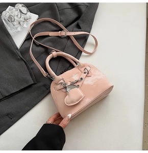 Détails du sac à main en cuir verni rose avec chaîne en métal et pendentif coeur