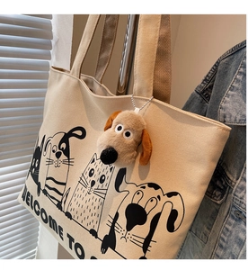 Detail of beige canvas tote bag with cute animal illustrations and plush dog pendant