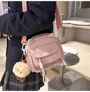 Détail du sac bandoulière rose avec oreilles de chat, poche transparente et gri-gri