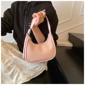 Pink crescent underarm bag with crocodile texture carried by a model on stairs