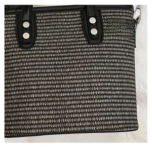 Detail of woven fabric texture with black leather trim and silver rivets on a summer bag