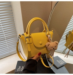 Detail of yellow lychee textured bucket bag with plush bear charm and fashion stamp