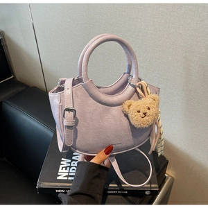 Detail of lavender pleated bucket bag with plush bear charm and adjustable strap