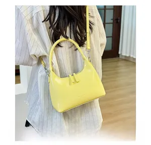 Rear view of a model wearing the bright yellow crescent shoulder bag in soft indoor light