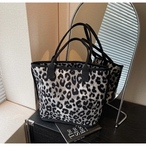 Detailed view of leopard print tote bag reflected in a mirror on a dark surface