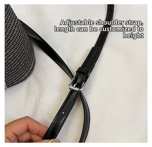 Detail of adjustable black leather strap with silver buckle for woven bucket bag
