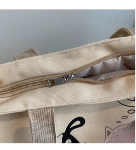 Macro detail of high-density canvas tote with silver metal zipper closure and cat print