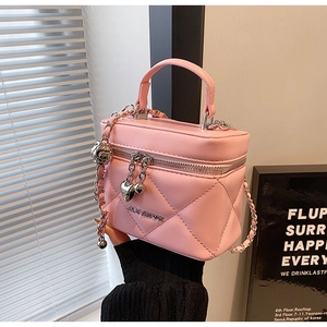Detailed shot of pink quilted crossbody box bag with heart zipper and chain strap