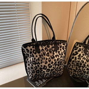 Detail of leopard print knit tote bag featuring black woven handles and textured fabric