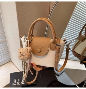 Detail of retro leather bucket bag featuring two-tone contrast and cute bear charm