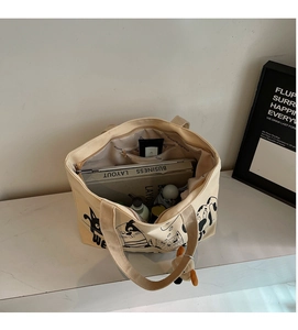 Detail view of large canvas tote bag showing interior capacity with laptop and cosmetics